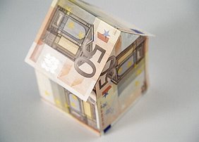 Gefaltete Geldscheine, die ein Haus darstellen