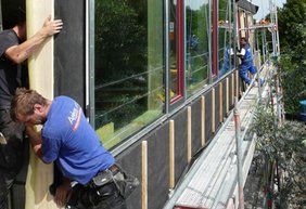 Arbeiter beim Anbringen der vorgefertigten Fassadenteile